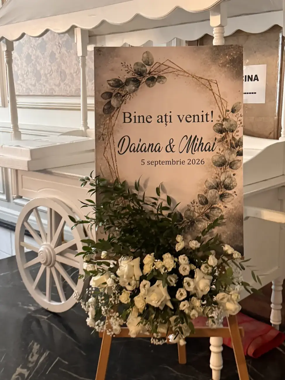 Panoul de bun venit al mirilor, lângă o trăsurică albă