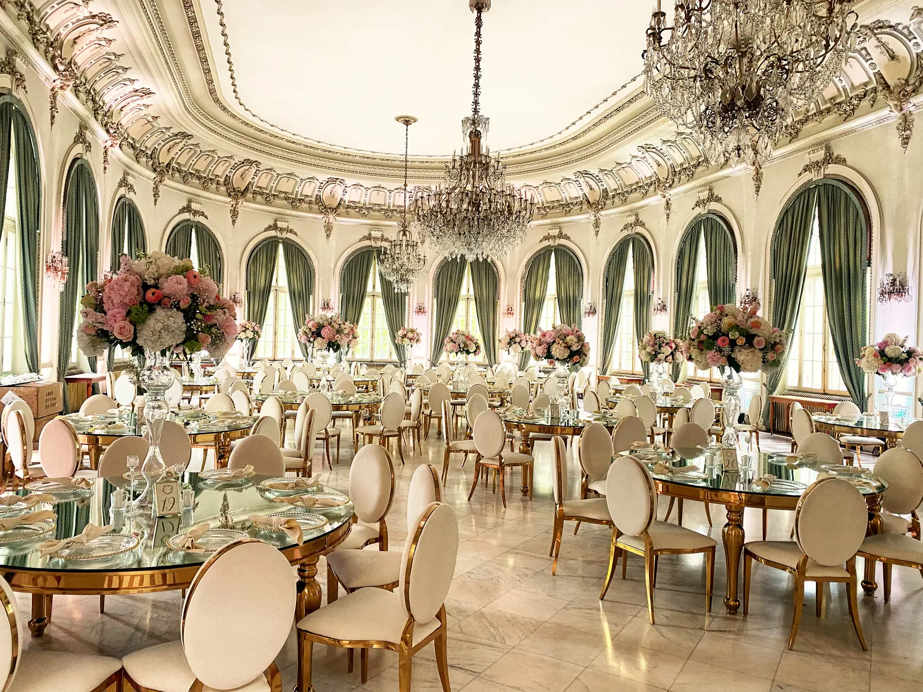 Sala ovală a Cazinoului din Sinaia, cu mese aurii și aranjamente florale roz